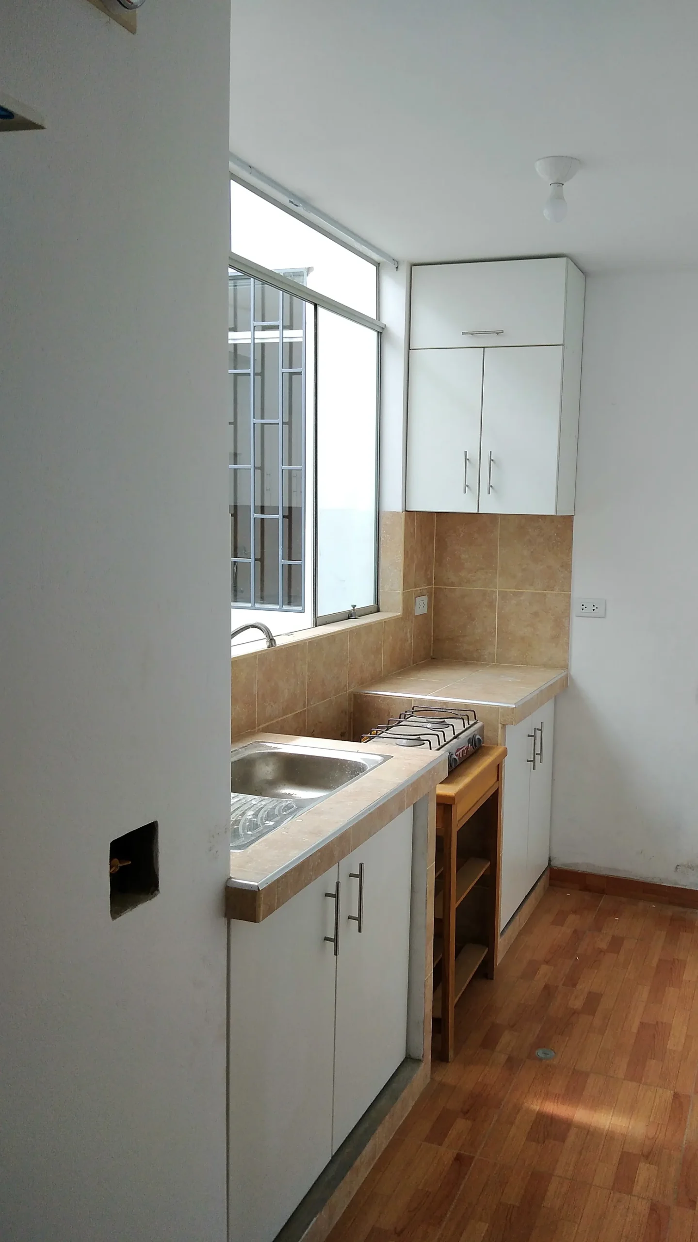 Mueble de TV blanco con iluminación e interrumptor, wallpanel, puerta de aluminio con vitrina, botellero, compartimento oculto, puertas de melamina con bisel a 45° y placa decorativa PVC, Puente Piedra.